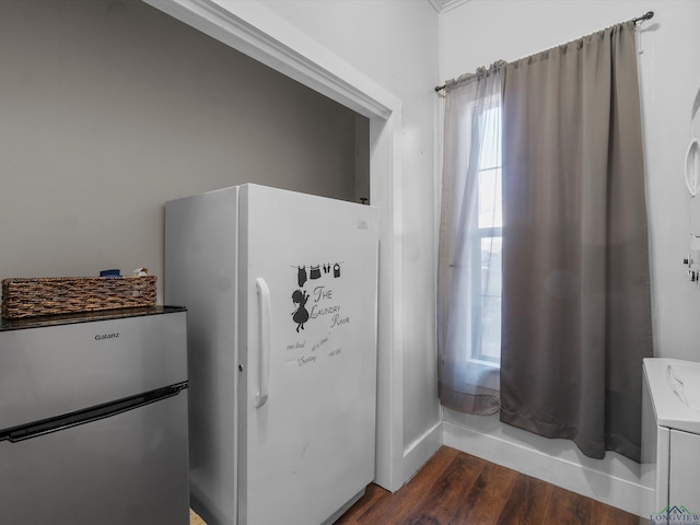 interior space featuring dark wood-type flooring, washer / clothes dryer, and freestanding refrigerator