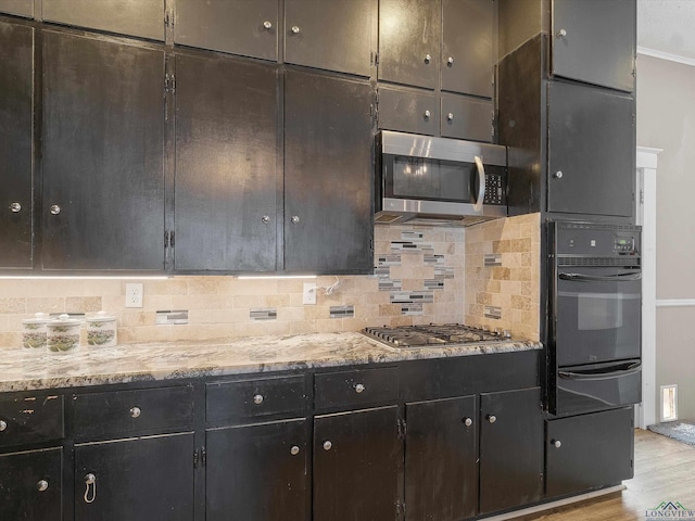 kitchen with a warming drawer, light stone counters, wood finished floors, stainless steel appliances, and decorative backsplash