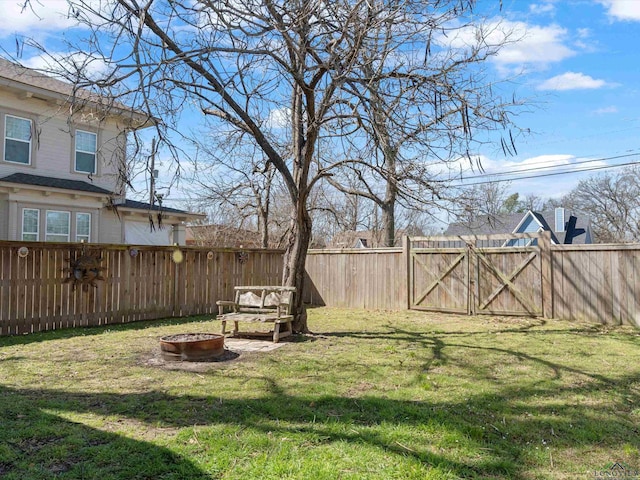 view of yard with a gate, fence, and an outdoor fire pit