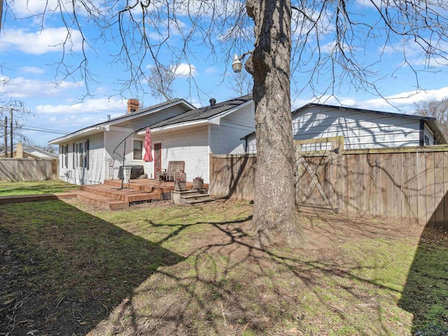 rear view of property featuring a deck, a yard, fence, and a chimney