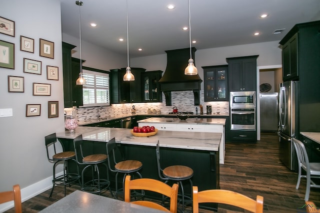 kitchen featuring backsplash, kitchen peninsula, decorative light fixtures, appliances with stainless steel finishes, and custom exhaust hood