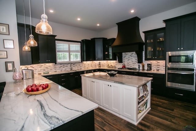 kitchen with decorative light fixtures, a kitchen island, light stone countertops, and stainless steel appliances