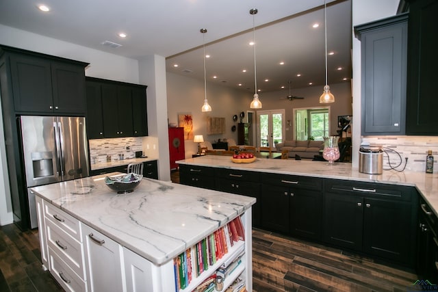 kitchen with stainless steel fridge, french doors, light stone counters, white cabinets, and a center island