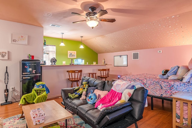 living room featuring ceiling fan, light hardwood / wood-style floors, and vaulted ceiling