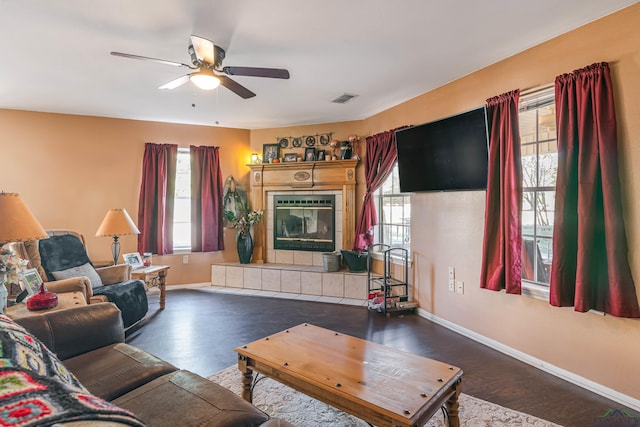 living room with dark hardwood / wood-style flooring, ceiling fan, and a tiled fireplace