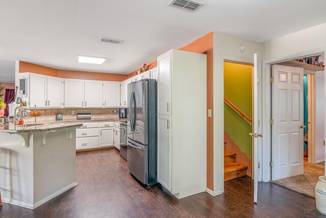 kitchen featuring light stone countertops, appliances with stainless steel finishes, white cabinets, and a breakfast bar area