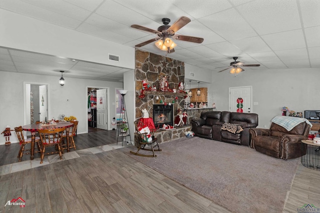 living room featuring a fireplace, ceiling fan, hardwood / wood-style floors, and a drop ceiling