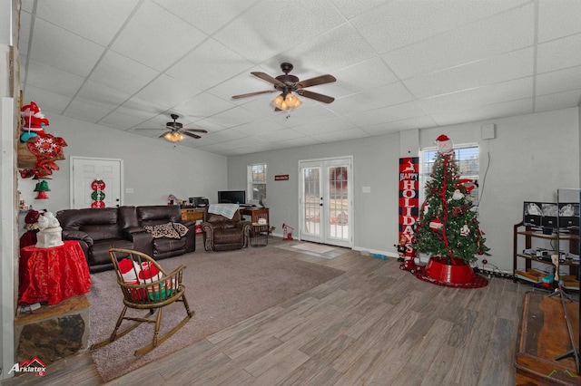 living room with a paneled ceiling, ceiling fan, hardwood / wood-style flooring, and french doors