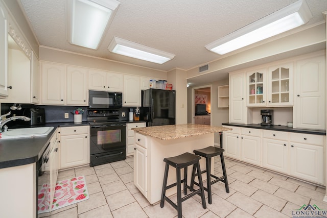 1002 Ruby St, Gilmer, TX 75644 - kitchen with a sink, black appliances, light tile patterned floors, visible vents, and a kitchen island