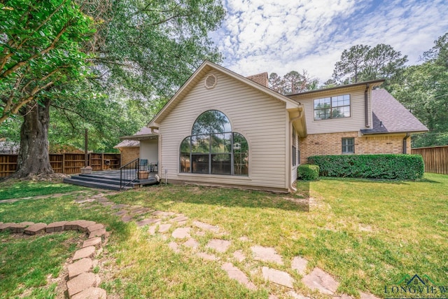 1002 Ruby St, Gilmer, TX 75644 - back of house with a fenced backyard, brick siding, a yard, and a deck