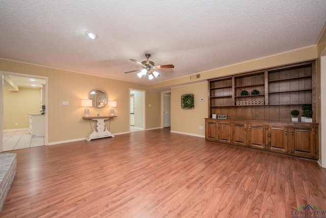 1002 Ruby St, Gilmer, TX 75644 - unfurnished living room with a textured ceiling, light wood-type flooring, visible vents, and ceiling fan