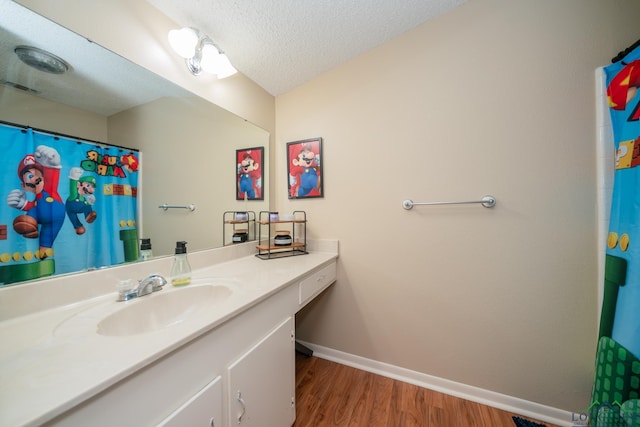 1002 Ruby St, Gilmer, TX 75644 - bathroom with wood finished floors, vanity, baseboards, a shower with shower curtain, and a textured ceiling