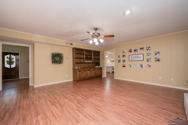 1002 Ruby St, Gilmer, TX 75644 - unfurnished living room featuring a textured ceiling, light wood-type flooring, baseboards, visible vents, and ceiling fan