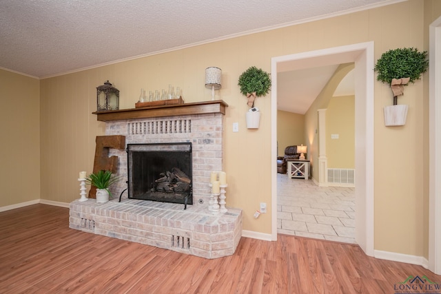 1002 Ruby St, Gilmer, TX 75644 - living area with wood finished floors, a textured ceiling, ornamental molding, a brick fireplace, and visible vents