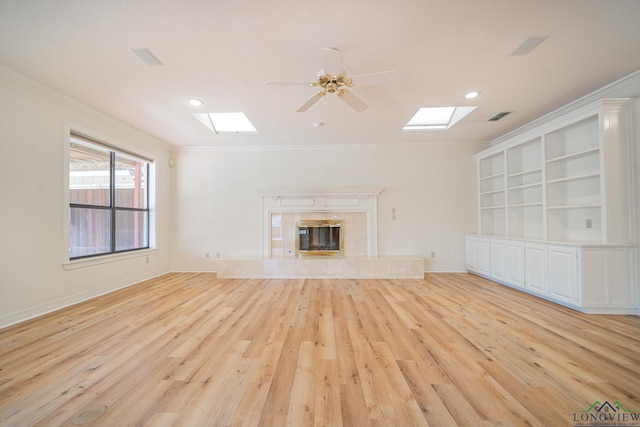 807 Vicksburg Ct, Longview, TX 75601 - unfurnished living room featuring a skylight, ornamental molding, light wood-style floors, ceiling fan, and a high end fireplace