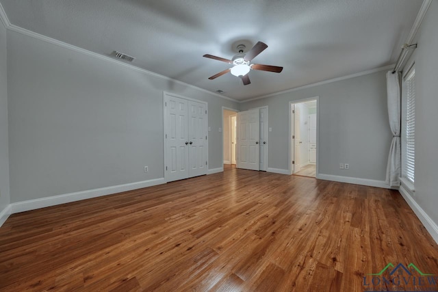 unfurnished bedroom with crown molding, ceiling fan, wood-type flooring, and ensuite bath