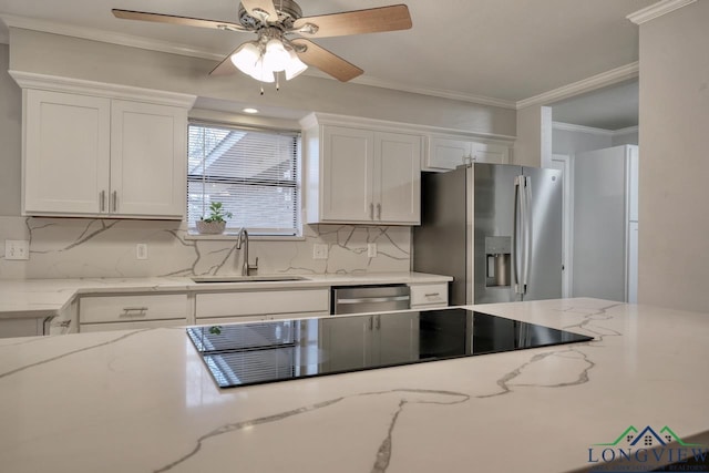 kitchen with sink, backsplash, stainless steel appliances, light stone countertops, and white cabinets