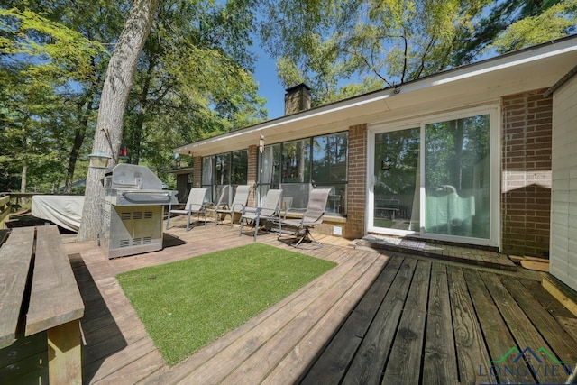 wooden deck featuring grilling area and a lawn