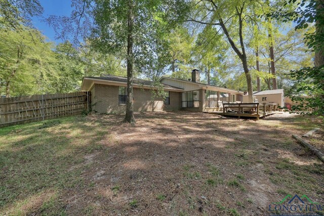 back of property with a wooden deck and a storage shed