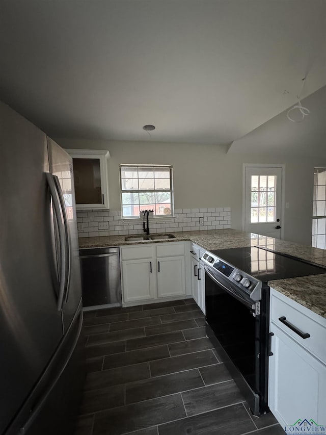 kitchen featuring appliances with stainless steel finishes, white cabinetry, sink, dark stone counters, and kitchen peninsula