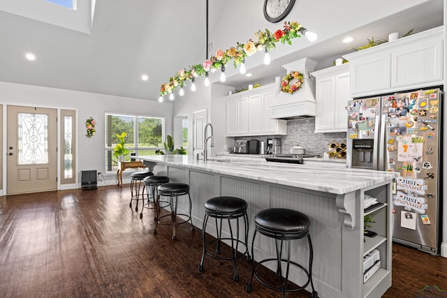 22732 Interstate 20e, Winona, TX 75792 - kitchen with stainless steel fridge, high vaulted ceiling, a kitchen breakfast bar, backsplash, and white cabinetry