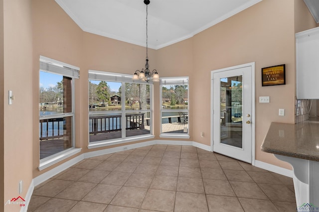 unfurnished dining area featuring baseboards, ornamental molding, a water view, tile patterned floors, and a chandelier