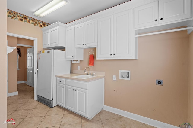 kitchen with light countertops, light tile patterned floors, freestanding refrigerator, white cabinets, and a sink