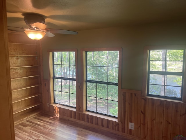 1483 County Road 1596, Avinger, TX 75630 - spare room featuring a ceiling fan, wood finished floors, a wainscoted wall, and wood walls