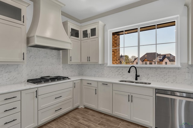 kitchen featuring appliances with stainless steel finishes, premium range hood, tasteful backsplash, sink, and white cabinetry