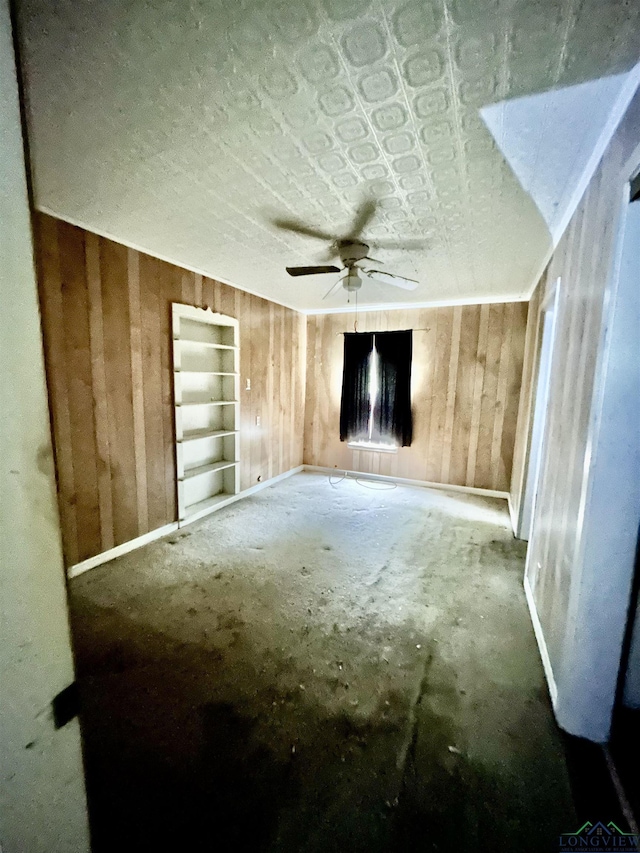 spare room featuring baseboards, wood walls, and ceiling fan