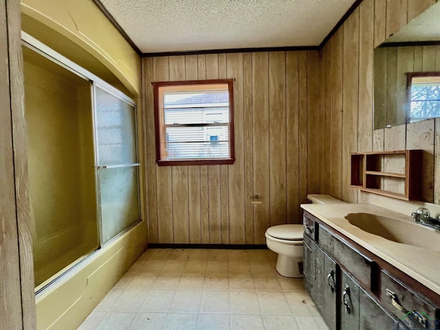 full bathroom featuring a textured ceiling, toilet, wooden walls, vanity, and combined bath / shower with glass door