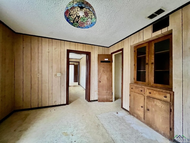 empty room featuring wood walls, visible vents, and a textured ceiling