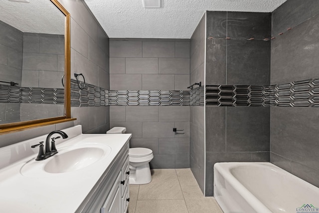 bathroom featuring a bathing tub, tile patterned flooring, tile walls, and vanity