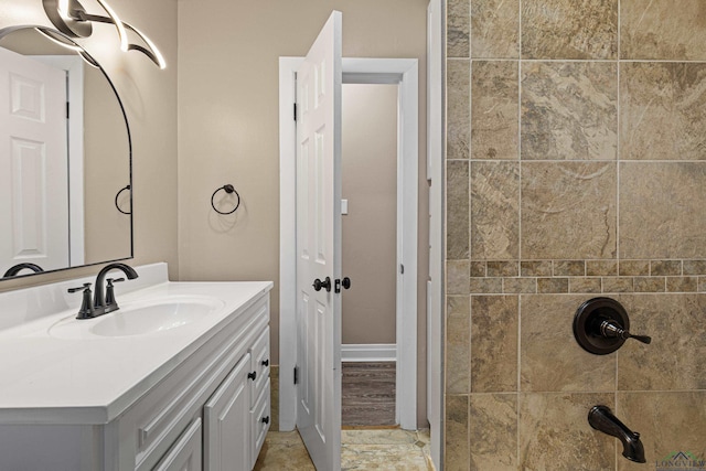 bathroom with a tile shower and vanity