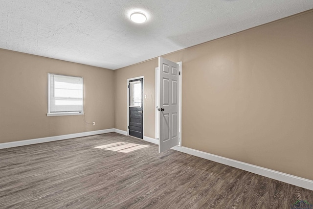 empty room with dark hardwood / wood-style flooring and a textured ceiling