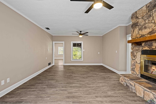 unfurnished living room with ceiling fan, a fireplace, hardwood / wood-style floors, ornamental molding, and a textured ceiling