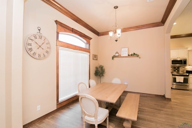 dining area with a chandelier, wood-type flooring, and ornamental molding