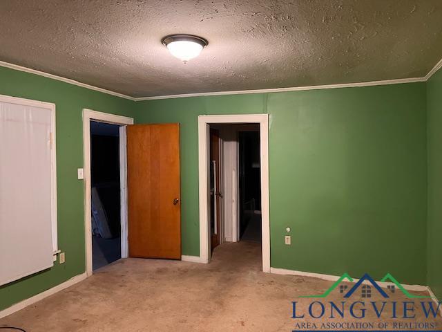 unfurnished bedroom featuring light colored carpet, ornamental molding, a textured ceiling, and a closet