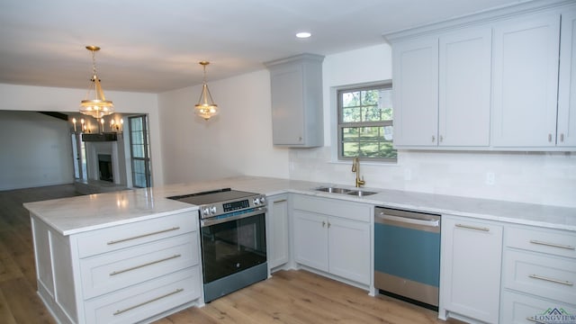 kitchen with hanging light fixtures, kitchen peninsula, sink, appliances with stainless steel finishes, and white cabinetry