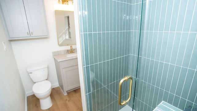 bathroom featuring vanity, hardwood / wood-style flooring, toilet, and a shower with door