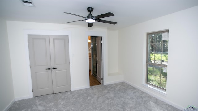 unfurnished bedroom featuring connected bathroom, ceiling fan, a closet, and light colored carpet