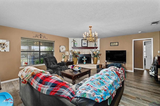 living room with a textured ceiling, dark hardwood / wood-style flooring, a chandelier, and a fireplace