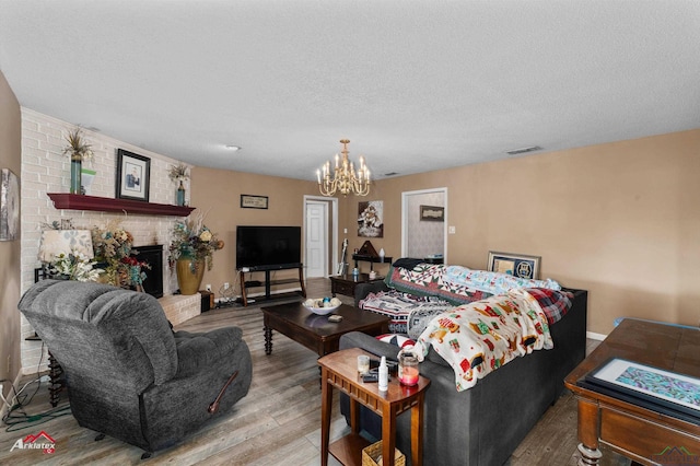 living room with a textured ceiling, an inviting chandelier, a fireplace, and wood-type flooring