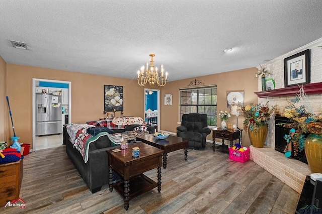 living room with a fireplace, hardwood / wood-style flooring, a textured ceiling, and an inviting chandelier