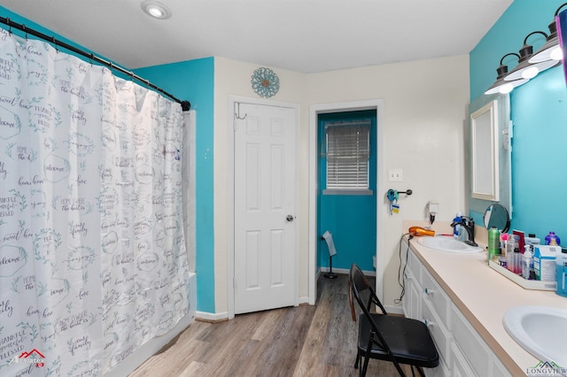 bathroom with wood-type flooring, shower / bath combination with curtain, and vanity