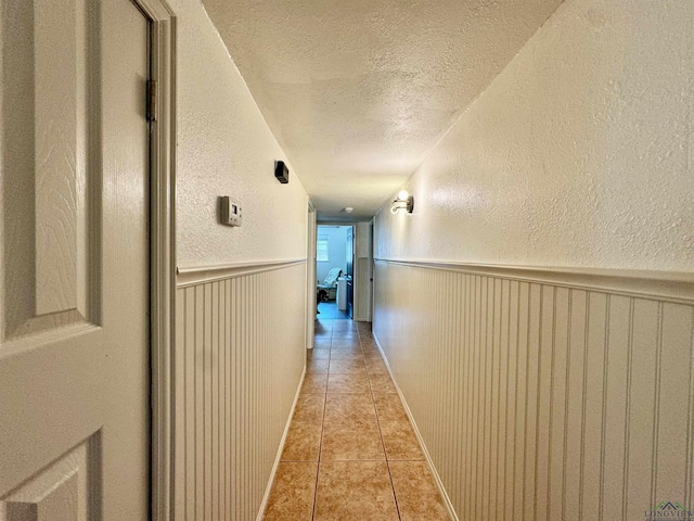 hallway featuring a textured ceiling and light tile patterned floors