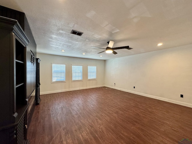 unfurnished living room with ceiling fan, a textured ceiling, and dark hardwood / wood-style flooring