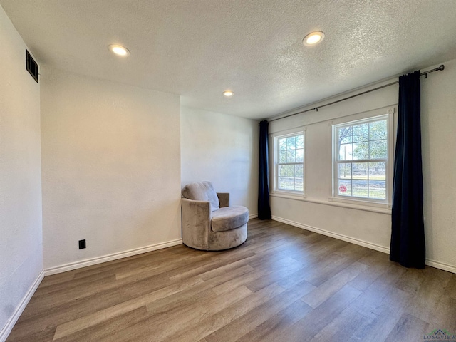 unfurnished room featuring wood-type flooring and a textured ceiling