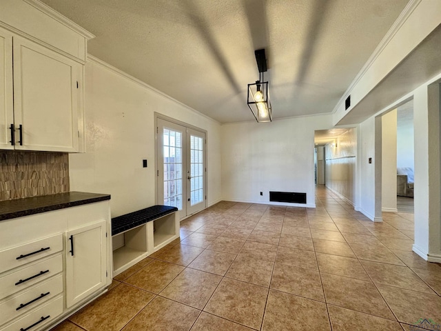 interior space featuring french doors, crown molding, a textured ceiling, and light tile patterned floors