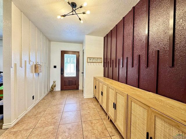 mudroom featuring light tile patterned floors, a notable chandelier, and a textured ceiling